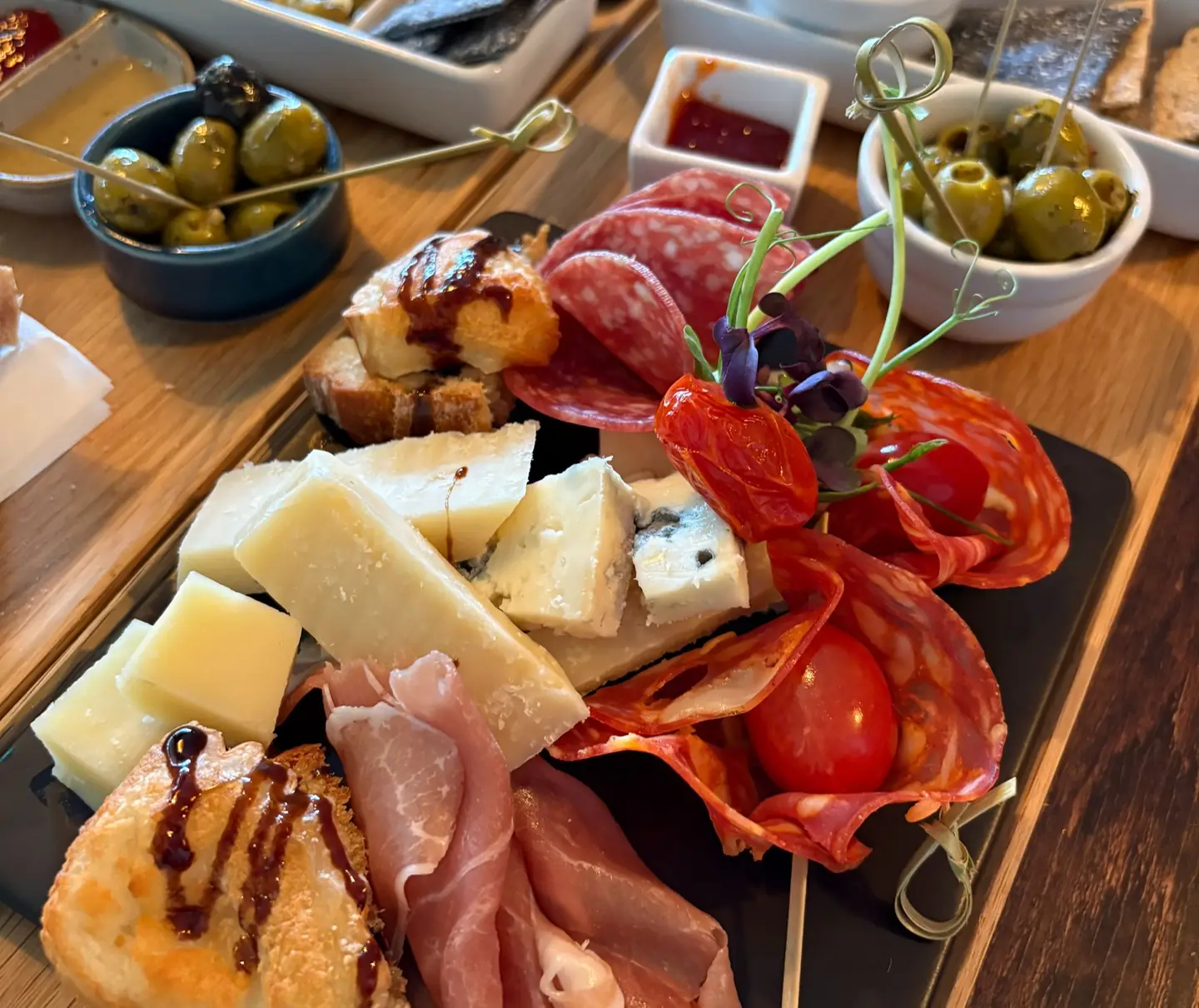 A board of Italian cheeses, cured meats and olives on a wooden table at Marcio’s