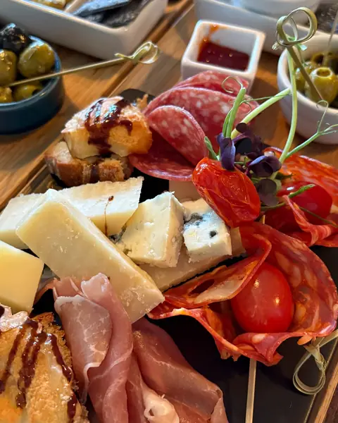 A board of Italian cheeses with salami, prosciutto, tomatoes and olives