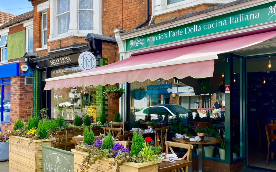 Marcio’s on Castle Road: the green fascia reading “Marcio’s l’arte della cucina Italiana”, a red scalloped awning and planters on the front terrace