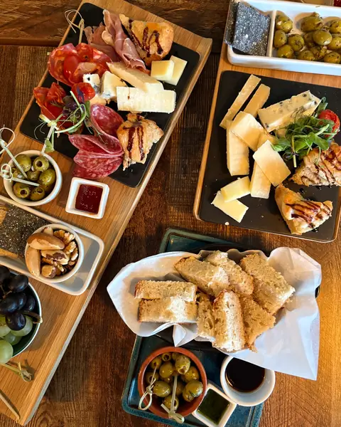 Sharing boards of cheeses, cured meats, olives and bread, seen from above
