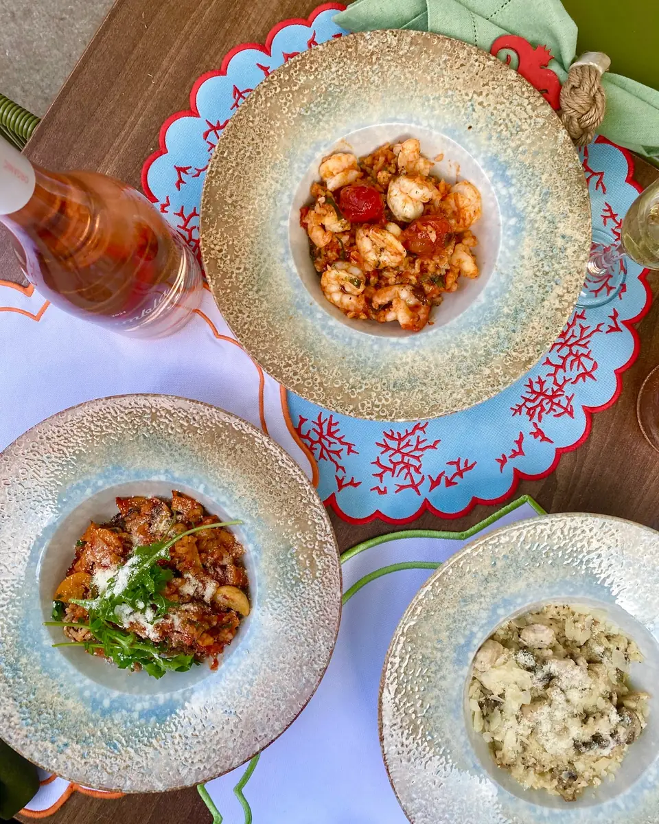 Prawns, pasta and risotto in speckled bowls on a scalloped placemat